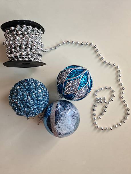 istock Frosted Elegance: Silver and Blue Christmas Ornaments with Beaded Garland on White Table 2237363558