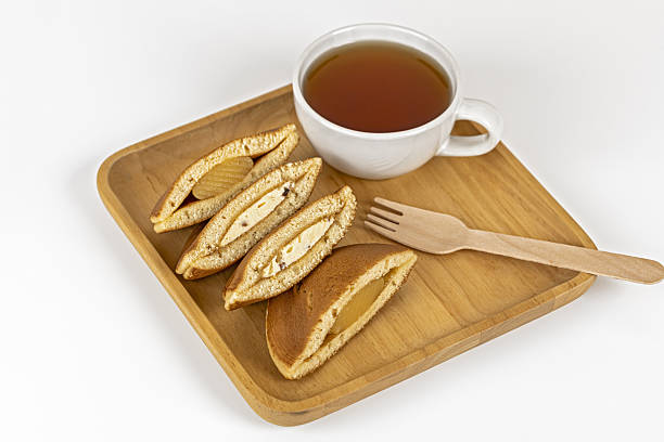A filled pancake, tea, wooden fork, and plate create cozy snack scene with warm tones and inviting atmosphere, perfect for breakfast or afternoon tea enjoyment