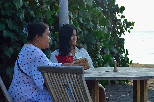 istock Mother and daughter quietly waiting for drinks at beach cafe 2237366551