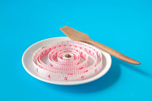 Measuring tape in white dish .Represents diet, portion control.