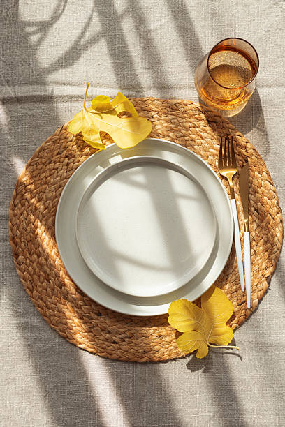 istock Table Setting with Yellow Leaves on White Plate and Woven Placemat under Sun Light 2237369758