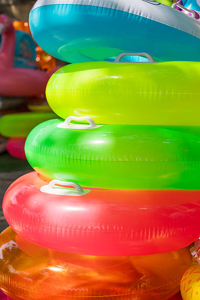istock Brightly colored inflatable pool floats are stacked together, creating a vibrant display near a swimming area. Perfect for summer fun and relaxation at the pool 2237374734