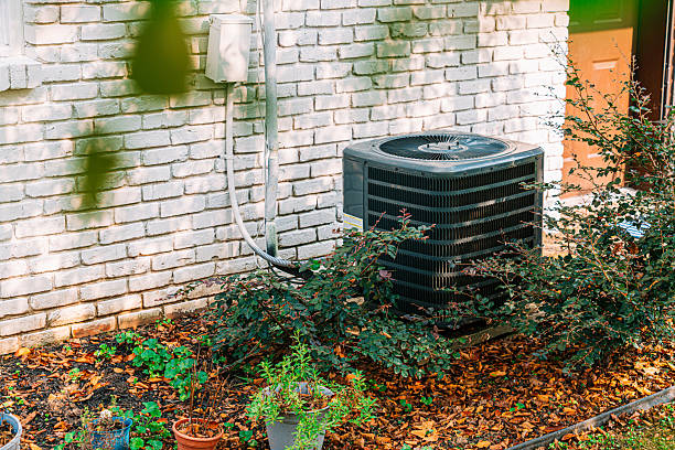 istock Greenery surrounding an Air Conditioning Condenser Unit Mounted on a Concrete Slab outside of a Suburban Brick Home in Tennessee in Late Summer / Autumn Season Change 2237382277