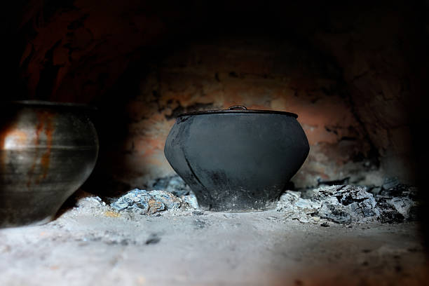 A cast-iron pot simmers over the coals in a Russian stove. Cooking delicious and healthy food in a Russian stove.