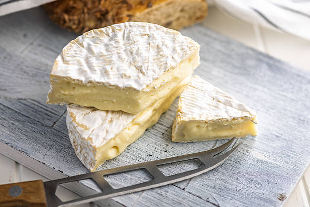 istock Camembert cheese on cutting board on white table. French cheese with mold on the surface. 2237391095