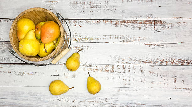 Small Wooden Basket Of Fall Bartlett Pears On Whitewashed Wood. Lots of copy space