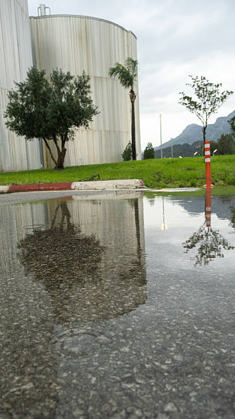istock An industrial complex dominated by a large, cylindrical metal tank can be seen. The structure is seen on a rainy day with trees beneath it. 2237396138
