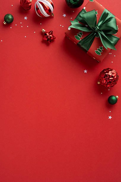 istock Vibrant vertical red backdrop with a wrapped gift featuring a green bow, plus festive ornaments and confetti suggesting Christmas and New Year celebrations with warm, joyful mood 2237400424