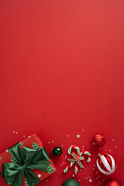 istock A vertical vibrant red holiday backdrop features a wrapped gift, candy canes, baubles, stars, and ribbons, signaling Christmas and New Year celebrations. Bright colors evoke joy, warmth, and festive cheer 2237400427