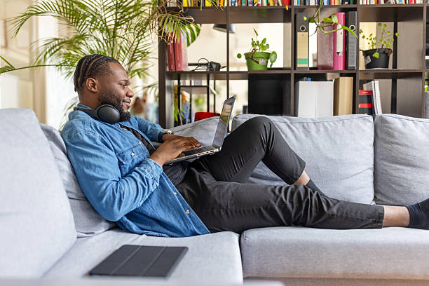 istock African businessman sitting comfortably on a sofa in office using laptop 2237401337