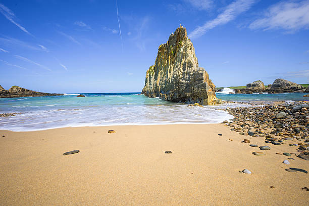 Playa de Mexota in Asturias, Spain, with its iconic central rock formation, sandy beach and turquoise Atlantic Ocean waves on the rugged coast