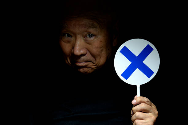 Old man holding a check mark and cross mark placard