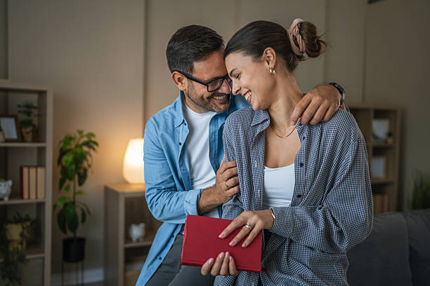 istock Happy smiling couple embracing at home reading book 2237412476