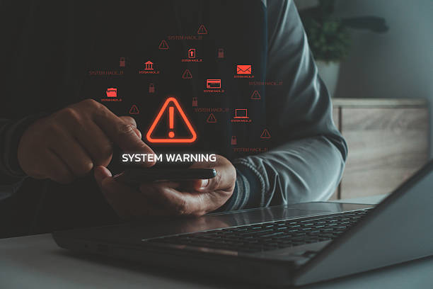 istock Cybersecurity alert with system warning and hacking risk symbols on mobile and laptop, concept of data breach, malware attack, phishing, cybercrime and information security threat in digital systems. 2237413512