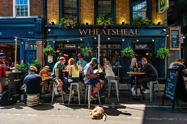 People relax at a pub at Borough Market, London, UK, on a sunny day.