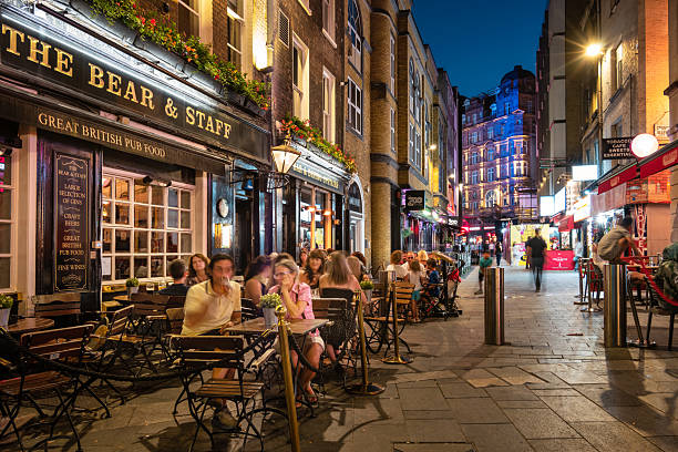 People relax on the patio of a pub at Leicester Square, London, UK, at night.