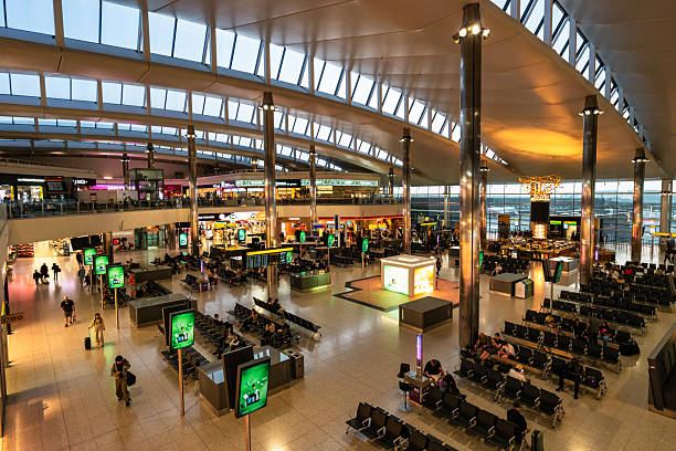 People walk inside Heathrow Airport Terminal 2 in London, UK, at dawn.