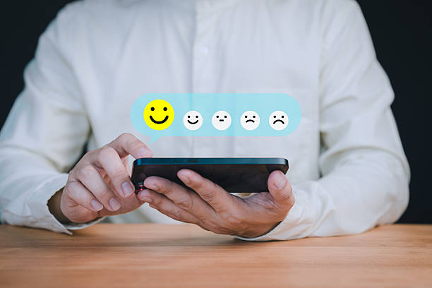 istock Person holding a smartphone select a happy face icon from a feedback scale with five emoji options, symbolizing customer satisfaction, review, and positive user experience in an online feedback system. 2237421798