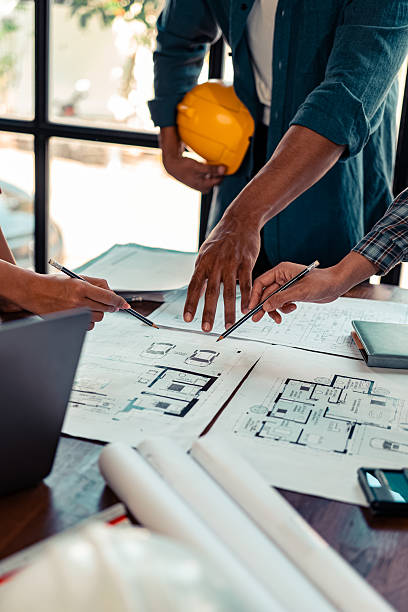 istock Architect checking blueprints on construction site Architects and engineers meet to discuss and check house plans to meet building and construction standards. 2237427945