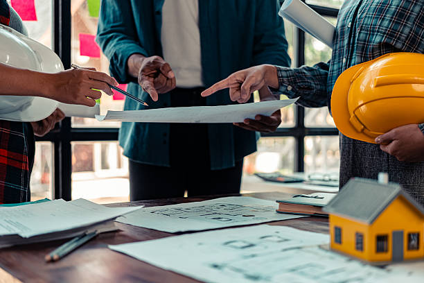 istock Architect checking blueprints on construction site Architects and engineers meet to discuss and check house plans to meet building and construction standards. 2237427963