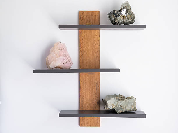 Creative interior decor with three mineral specimens, pink calcite, fluorite with pyrite and galena, displayed on gray shelves with wooden base.