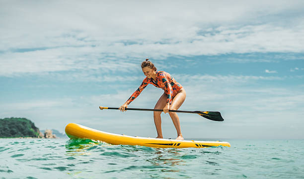 A woman with a paddle for a stand up paddle board, holding sup and laughing har