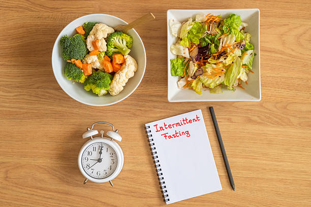 istock Healthy diet and intermittent fasting background with clock, fresh salad, vegetables, notepad and copy space for nutrition planning and weight control. 2237451939