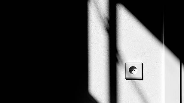 istock Minimalistic photo of a white wall socket with dramatic light and shadow contrast on the wall. 2237456173