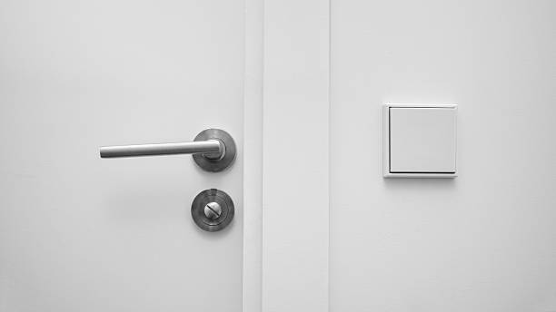 istock Minimalist white wall with a modern metal door handle and a light switch, interior detail in contemporary design. 2237456725