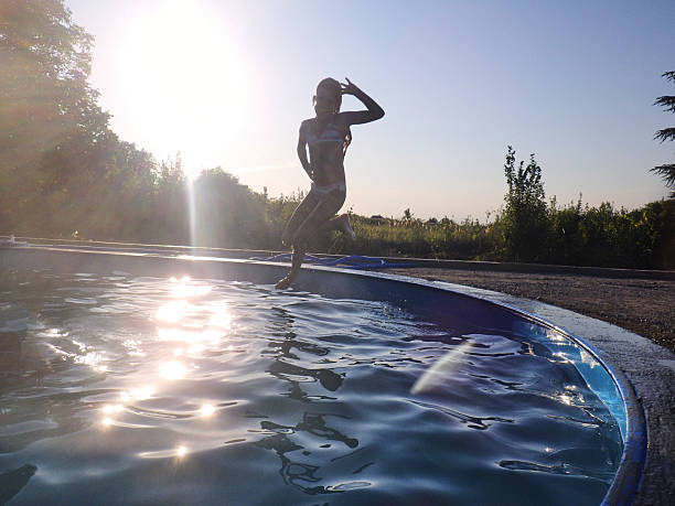 Happy teenage girls holding hands when jumping into the swimming pool