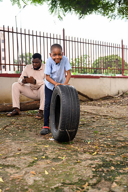 istock Smiling boy pushing a car tire outdoors 2237461344