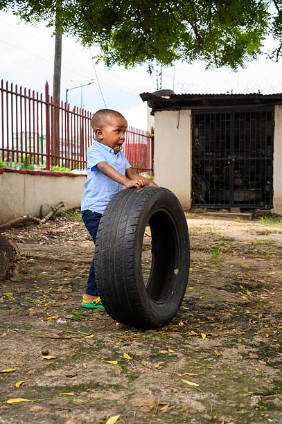istock Young boy pushing a car tire outdoors with playful expression 2237461439