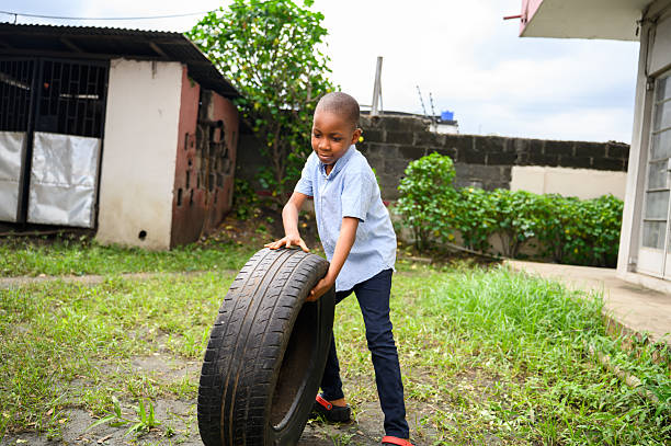 istock Boy lifting a car tire outdoors in grassy area 2237461991