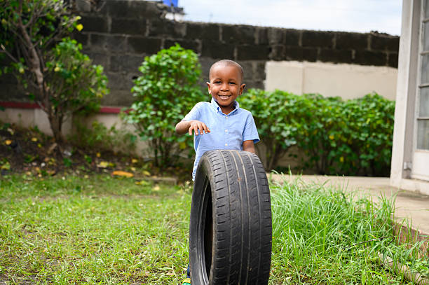 istock Smiling boy standing behind a car tire outdoors 2237462018
