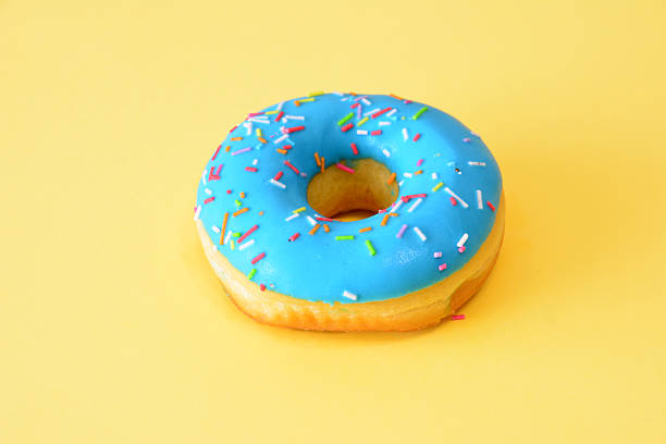 istock a blue donut with sprinkles isolated on the yellow background 2237462143
