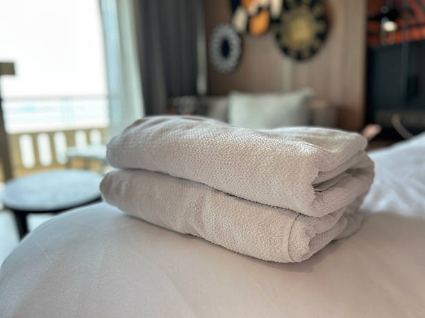 istock Neatly folded white towels stacked on a soft bed in a hotel room 2237464040