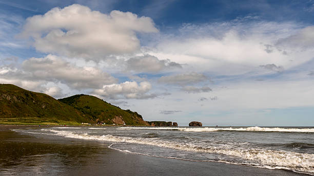 istock Waves rolling onto coastal shoreline with green hills 2237465169