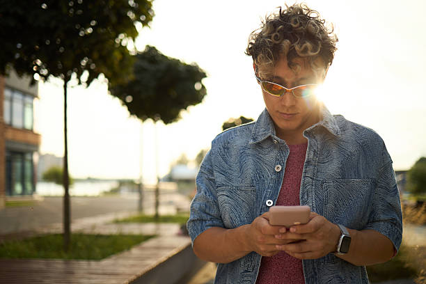istock Young Caucasian Man Using Smartphone Outdoors during Sunny Day 2237467216