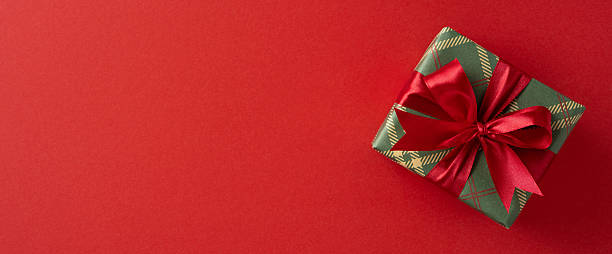 istock Wrapped banner gift box with a red ribbon rests on a bold red backdrop, conveying holiday magic, generosity, celebration, warmth, and festive charm suited for Christmas and New Year greetings 2237467267