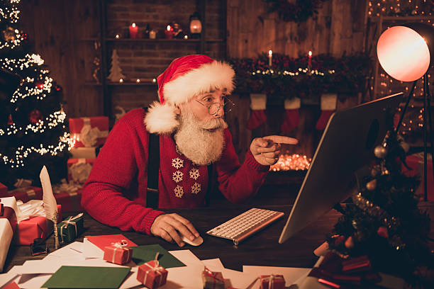 istock Photo portrait cheerful smiling santa pointing finger on computer screen keeping hand on mouse 2237469910