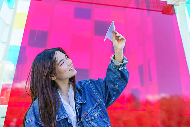 Young woman holding paper plane dreaming about future