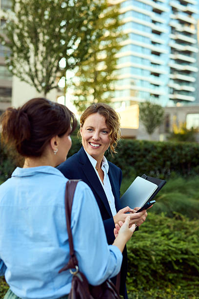 istock Professional Women Talking Outdoors With Tablet In City Park Setting 2237470559