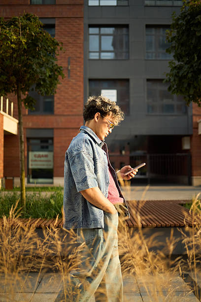 istock Young Caucasian Man Walking Outdoors Using Smartphone in Urban Setting 2237470825