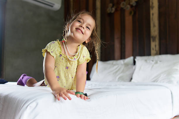Happy girl day dreaming while relaxing on a bed in bedroom.