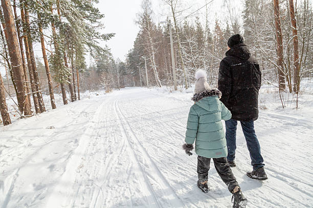istock Dad and daughter walking and having fun in snowy winter forest 2237473122