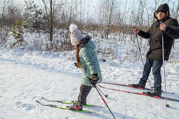 Dad and daughter skiing in the winter forest