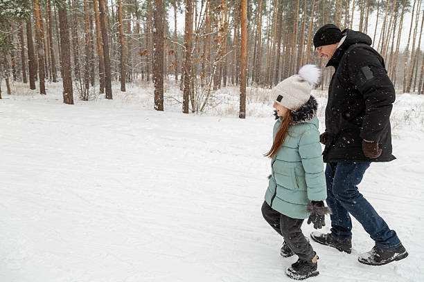 istock Dad and daughter walking and having fun in snowy winter forest 2237473711