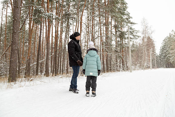 istock Dad and daughter walking and having fun in snowy winter forest 2237474267