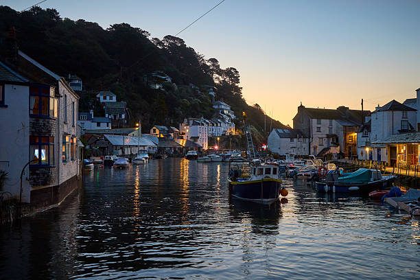 Polperro village and harbour cornwall, england, UK at high tide during sunrise. Polperro on the south east coast of cornwall still has a busy working harbour mainly used by local fishermen and tourist boat trips, the quaint cottages are typical of cornish villages.