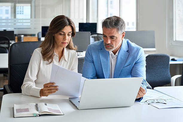 istock Two executives team working on laptop discussing documents at office meeting. 2237477152
